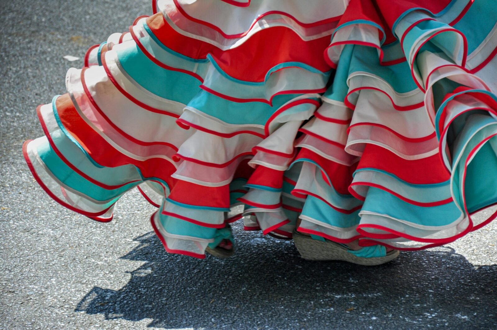 A vibrant flamenco skirt in red, teal, and white, captures traditional dance motion.